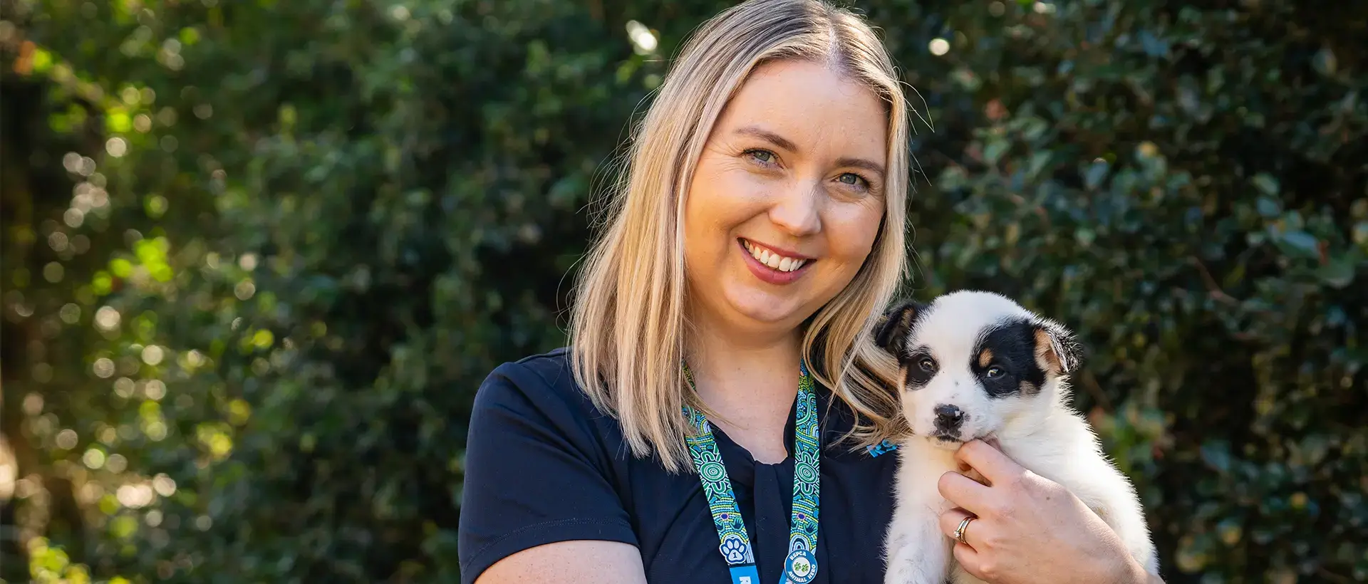 A woman holding a small black and white puppy outdoors